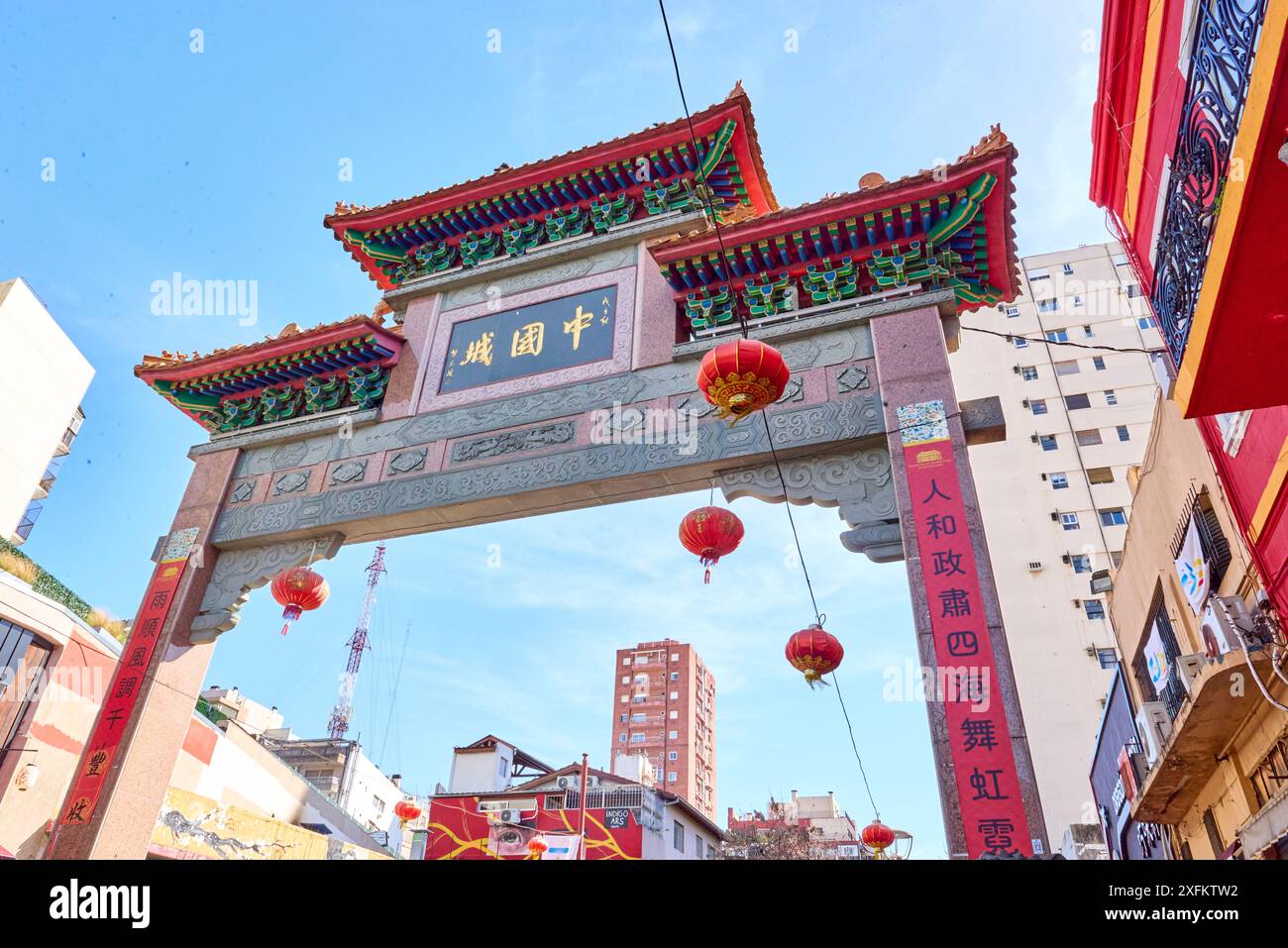 Chinesischer Bogen von unten gesehen. Es ist vielfarbig und sehr hoch und dient als Rahmen für die Straße und die dahinter liegenden Gebäude. Es gibt eine Variation von differen Stockfoto