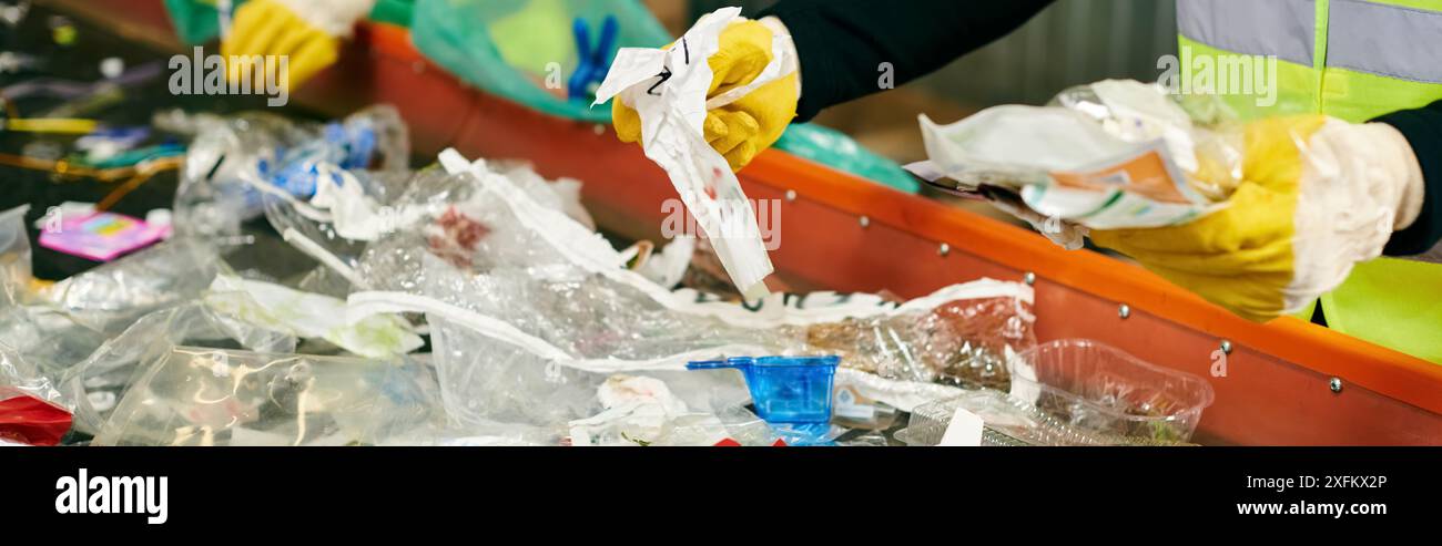 Eine Person in einer gelben Sicherheitsweste sammelt Plastikflaschen zusammen mit jungen Freiwilligen, die Müll für das Recycling sortieren. Stockfoto