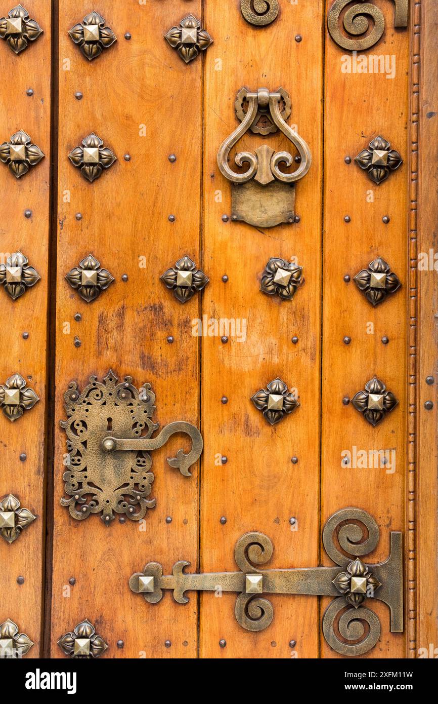 An der Tür sind viele dekorative Metallknöpfe angebracht. Die Tür ist aus Holz und hat einen goldenen Griff Stockfoto