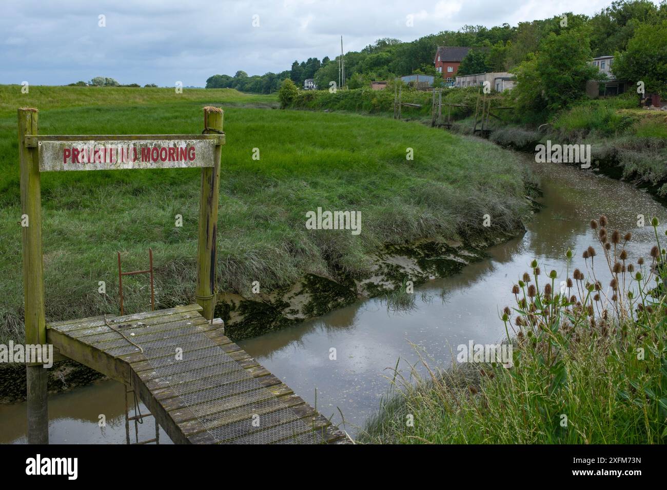 Private Anlegestelle Am Creek. Ein ruhiger Holzsteg führt zu einer privaten Anlegestelle an einem ruhigen Bach. Auf dem Schild steht „PRIVAT NO MOORING“ Stockfoto