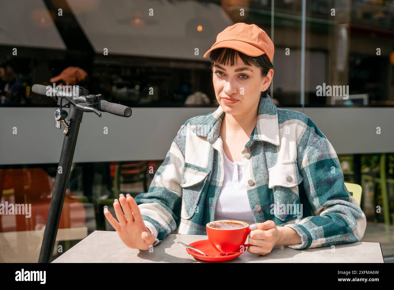 Eine unzufriedene Frau, die im Straßencafé mit einem Freund draußen Kaffee trinkt, Schild mit Halt, Lifestyle-Konzept negativer menschlicher Ausdruck und Körperlang zeigt Stockfoto
