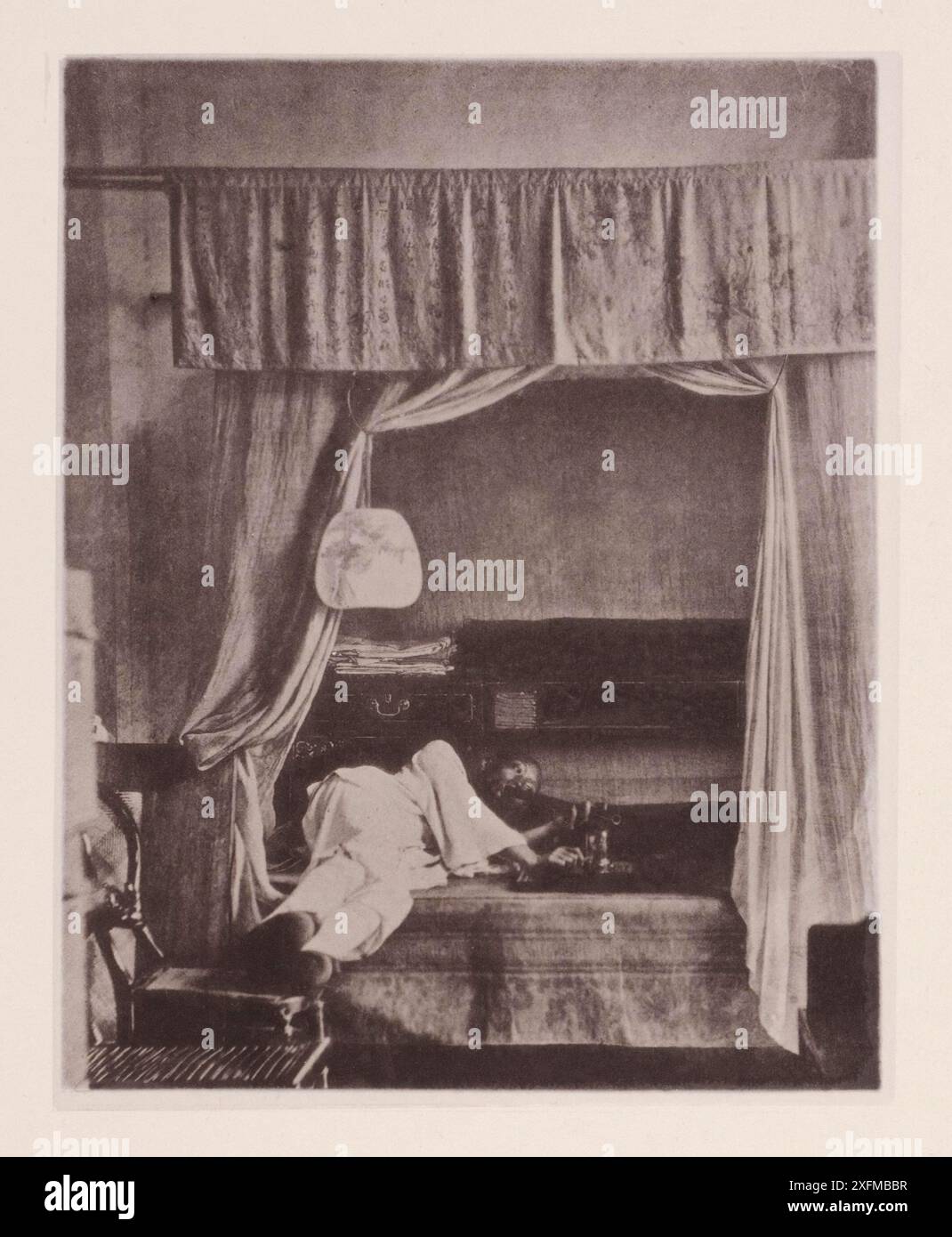 Vintage-Foto von einem Hauch Opium zu Hause. Illustrations of Qing China, 1875 dieses Bild zeigt die Methode, bei der Opium von den reicheren Klassen unter den Chinesen geraucht wird. Der Raucher hier hat Freizeit und Geld auf seinen Befehl, damit er sich frei dem Konsum der Droge hingeben kann. Seine Opiumpfeife ist ein beeindruckend aussehendes Instrument, das überhaupt nicht der "Shisha" Indiens oder der leichten Tabakpfeife ähnelt, die wir bei uns benutzen. Es besteht aus einem Metall- oder Bambusrohr, das an einem Ende ein breites Mundstück aufweist und am anderen Ende geschlossen ist. Opiumrauchen ist eines der versklavendsten Laster, das, wenn es so ist Stockfoto