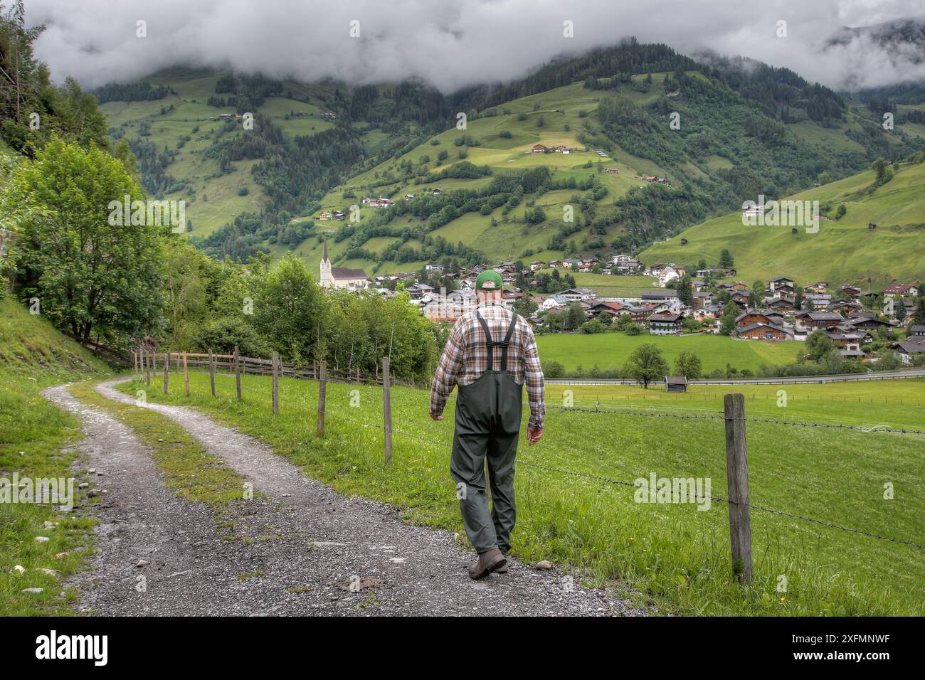 Ein Wanderer geht von der Almweide ins Tal. Vor ihm liegen die Häuser der Marktstadt Rauris in Österreich. Stockfoto