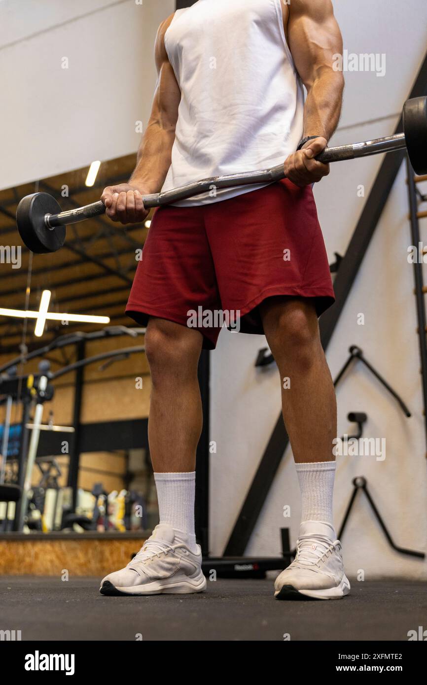 Starker Mann, der Bizeps mit einer Zick-Zack-Bar im Fitnessstudio trainiert. Stockfoto