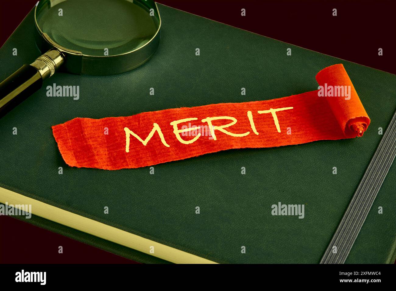 Business and Merit Concept. Kopierbereich. Das Konzept-Wort-Verdienstsymbol auf einem roten Blatt Papier, das auf einem grünen Geschäftsbuch liegt Stockfoto