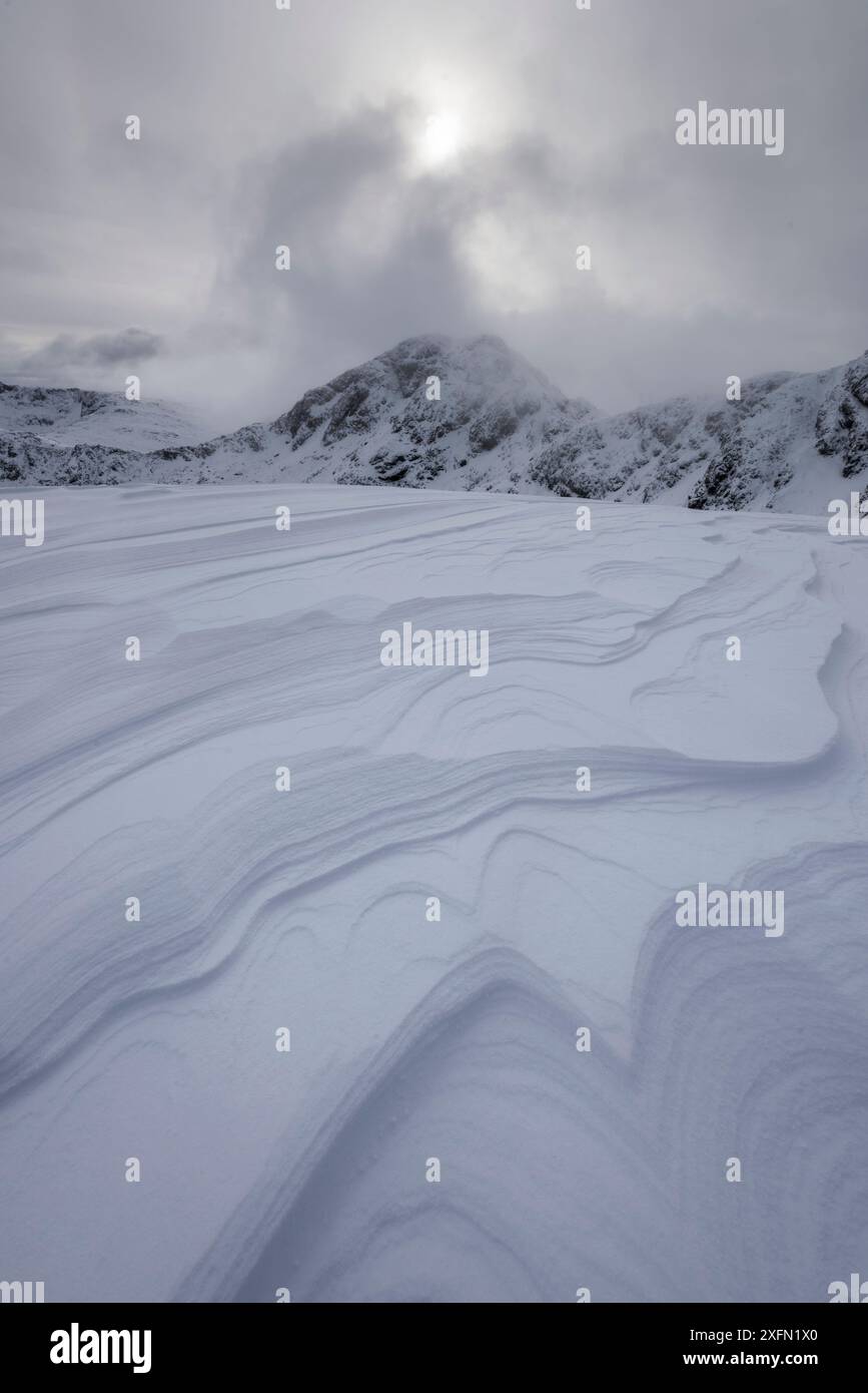 Wind schuf Muster in Schneeschichten auf Meall Dearg mit am Bodach im Hintergrund, Aonach Eagach, Glencoe, Schottland, Großbritannien, Februar 2017. Stockfoto