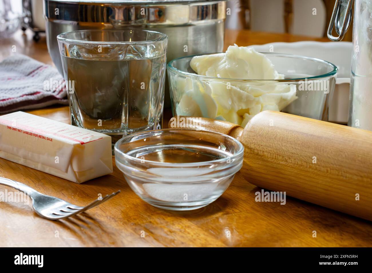 Zutaten für einen Kuchen, einschließlich: Schüssel mit Füllung, Butter, Salz, Wasser, Kürzen, und Mehl für die Kruste. Zu den Utensilien gehören eine Gabel, ein Tortenplatte und Stockfoto