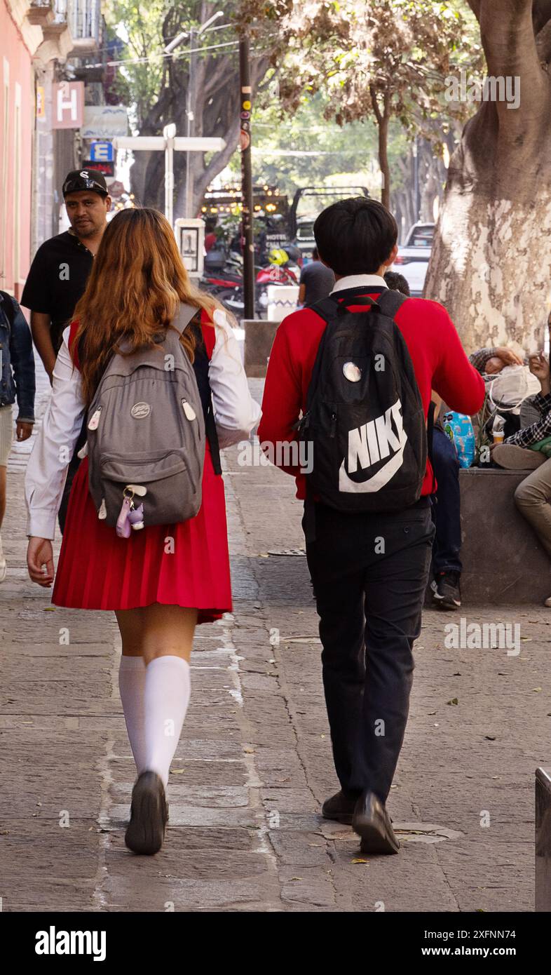 Mexikanische Schulkinder - Mädchen und Junge im Alter von 13 Jahren in Schuluniform, die auf der Straße laufen, Rückansicht, Puebla Mexico. Mexikanische Schulbildung Stockfoto