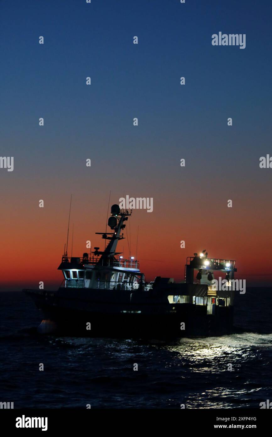 Der Sonnenaufgang bricht, als das Fischereischiff 'Harvester' ihre Angelausrüstung abfeuert. Nordsee. März 2016. Eigenschaft freigegeben. Stockfoto