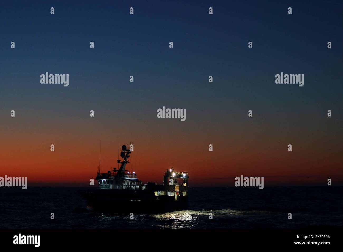 Der Sonnenaufgang bricht, als das Fischereischiff 'Harvester' ihre Angelausrüstung abfeuert. Nordsee. März 2016. Eigenschaft freigegeben. Stockfoto