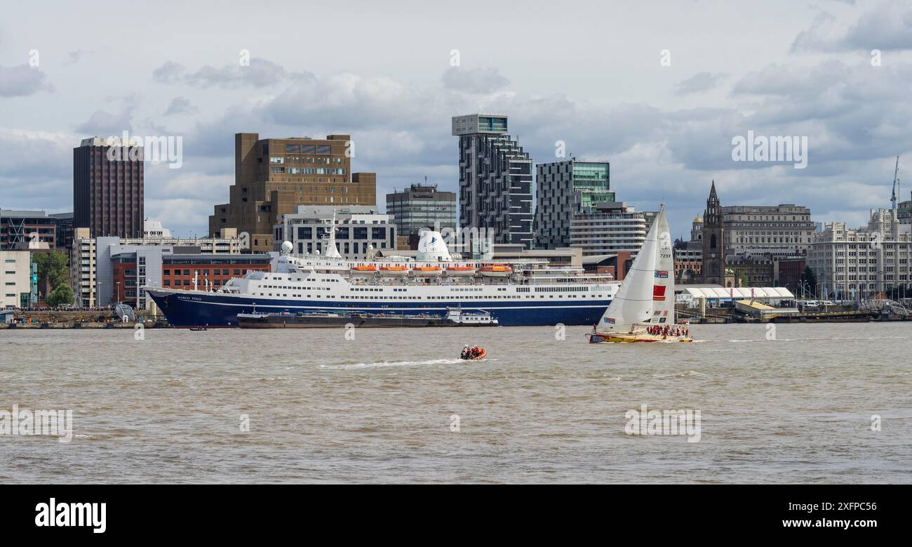 Eine Yacht, die direkt nach dem Beginn des Clipper Round the World Race 2017 an der Hafenpromenade von Liverpool vorbeifährt, wobei das Marco Polo Kreuzfahrtschiff an der Anlegestelle am Pier Head ankert. Merseyside, Großbritannien, August 2017. Stockfoto