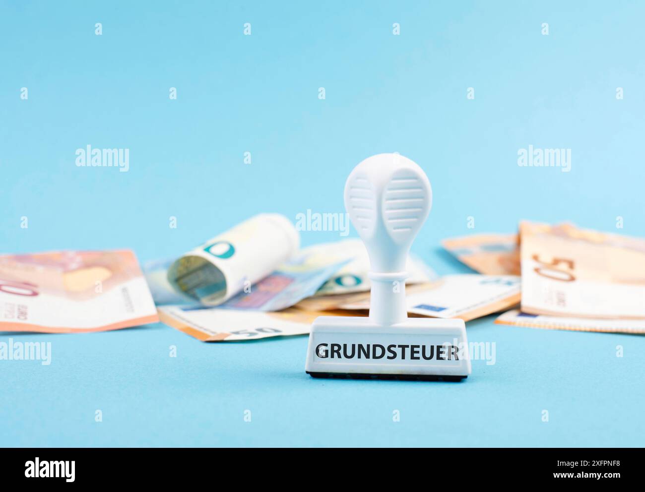 Euro-Banknoten und ein Stempel mit dem deutschen Wort für Grundsteuer, neues Wohnungsgesetz in Deutschland Stockfoto