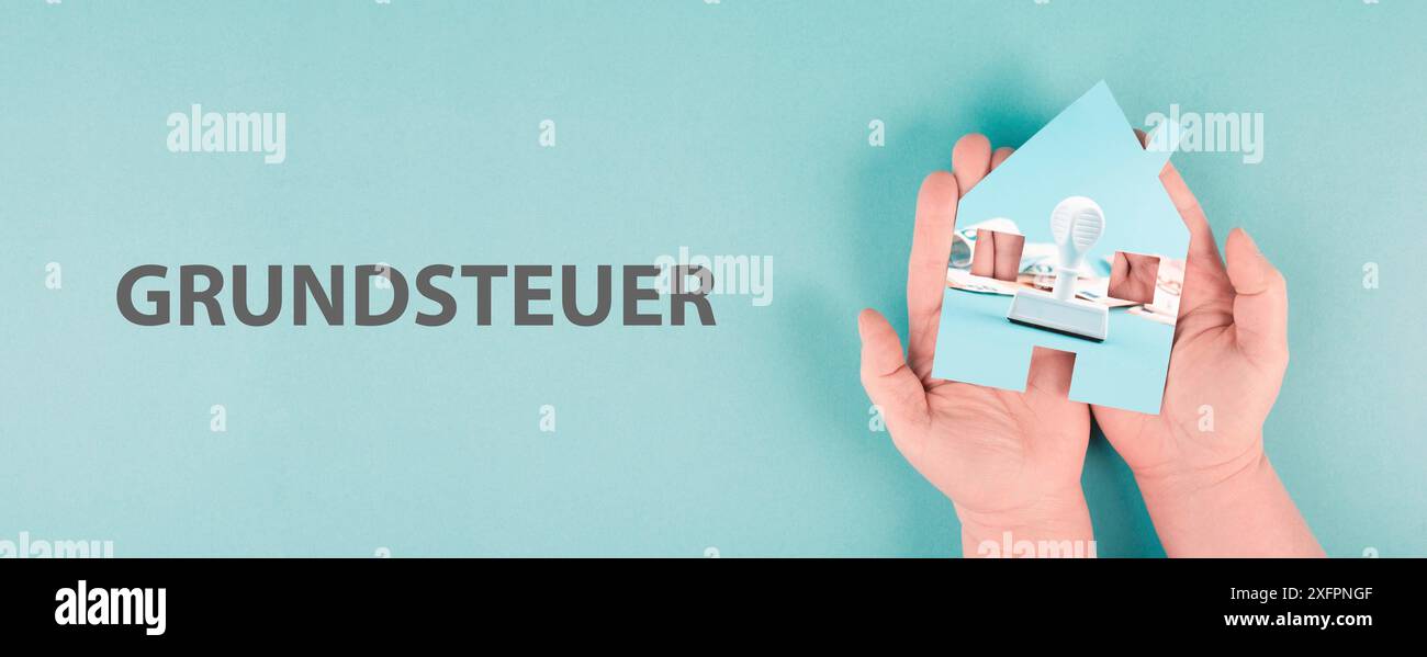 Ein Haus in der Hand halten mit Euro-Banknoten und einem Stempel, neues Grundsteuergesetz in Deutschland Stockfoto