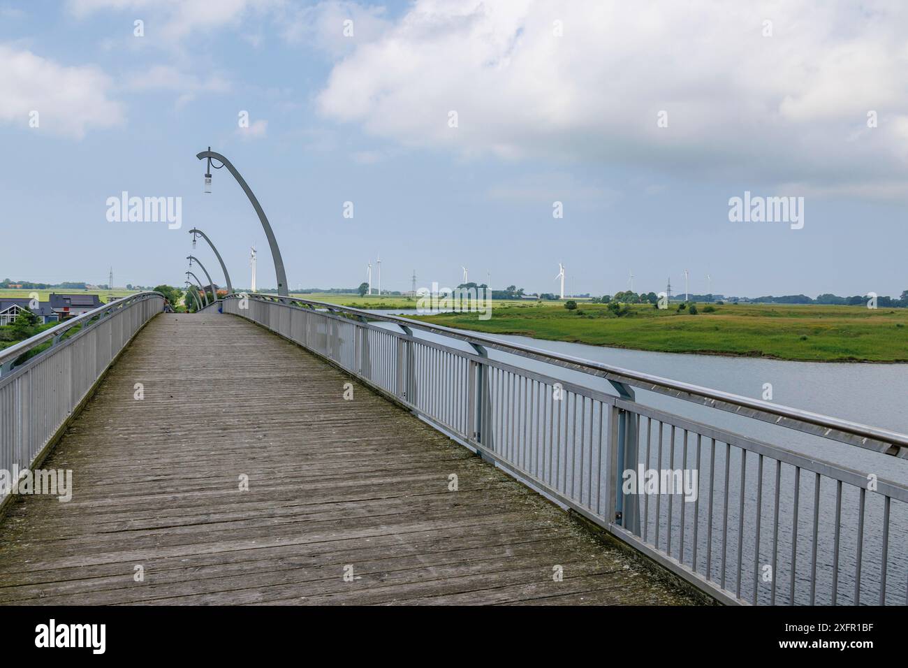 Lange Holzbrücke über einen Fluss in einer weiten Landschaft, wangerland, niedersachsen, deutschland Stockfoto