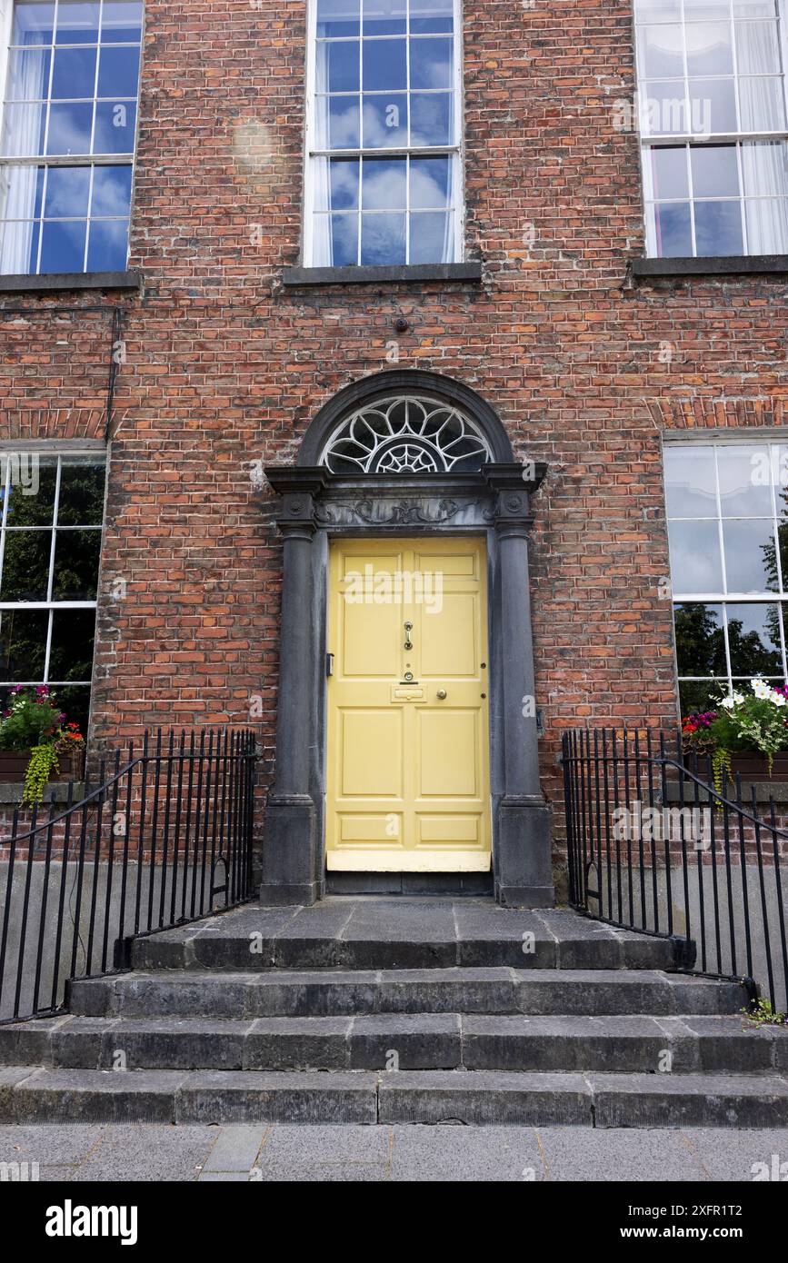 Ein historisches Backsteinhaus mit gelber Tür in Kilkenny, Irland. Stockfoto