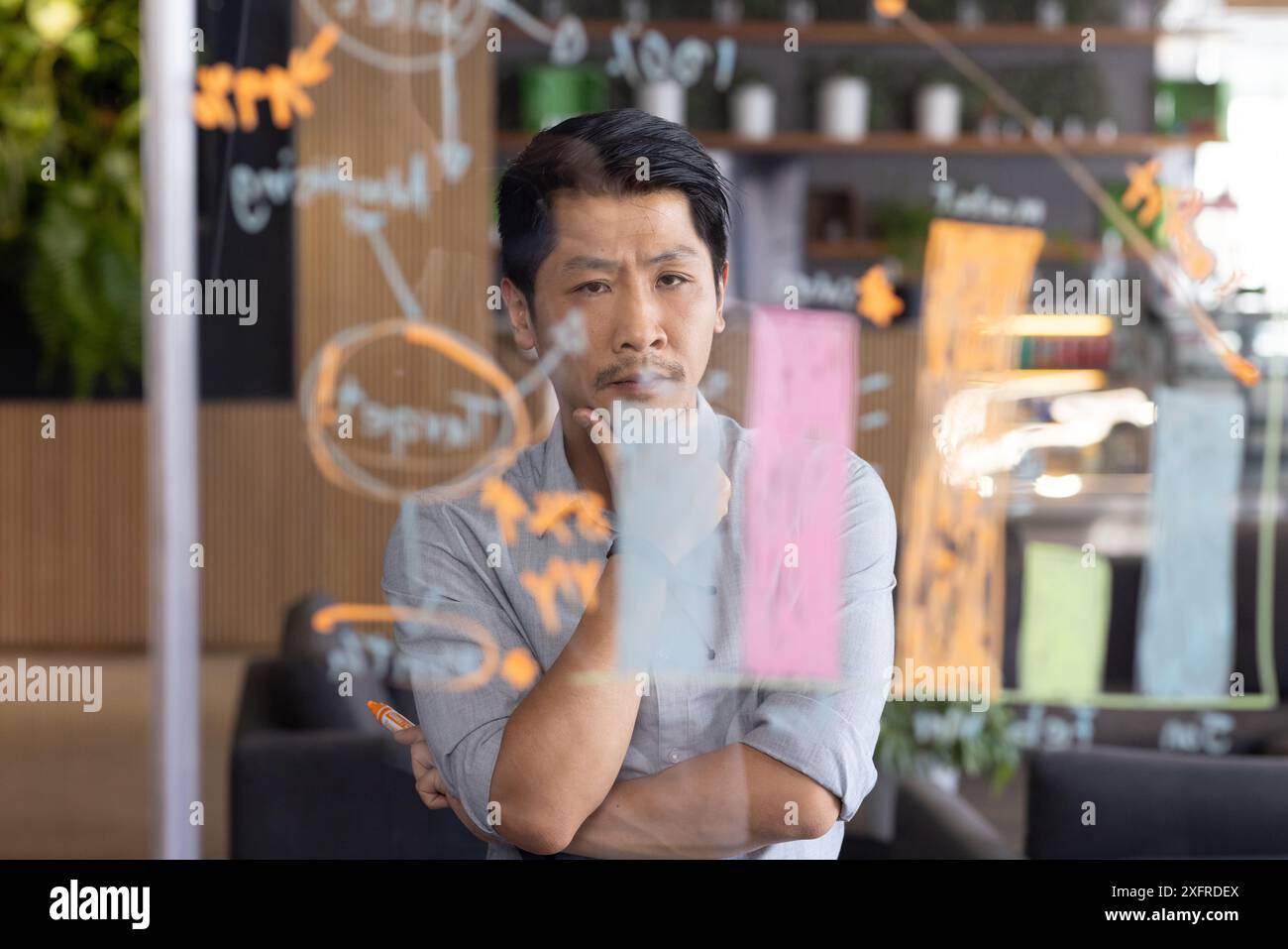 Ein Mann, der den Projektplan auf transparenter Tafel im Büro analysiert Stockfoto