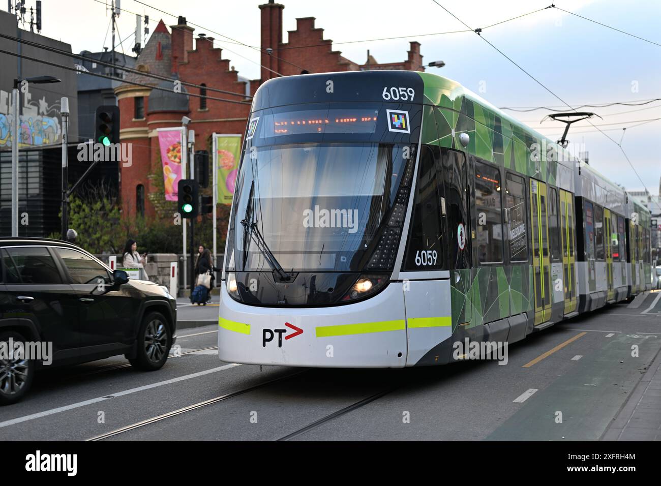 E-Klasse-Straßenbahn mit PTV-Lackierung und Logo, die am späten Nachmittag über den Fußgängerübergang vor dem Bahnhof South Yarra fährt Stockfoto