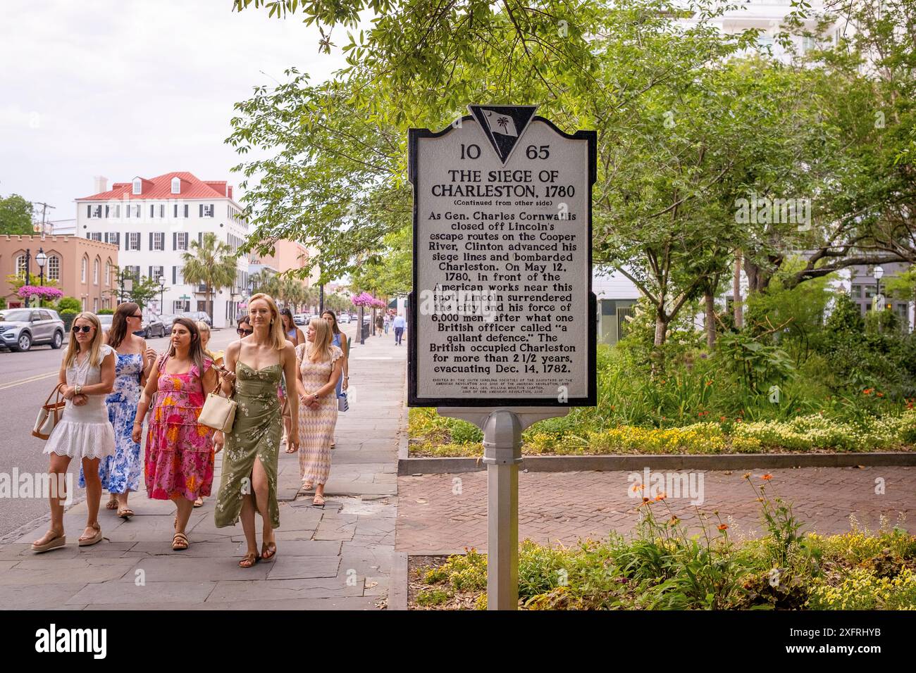 Frauen in Kleidern gehen neben einem historischen Schild im Zentrum von Charleston, South Carolina, USA Stockfoto