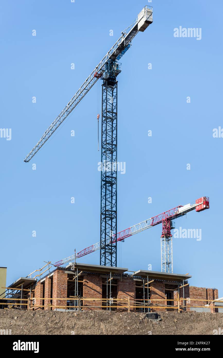 Ein Paar Bauturmkrane, die auf der Baustelle auf blauem Himmel arbeiten Stockfoto