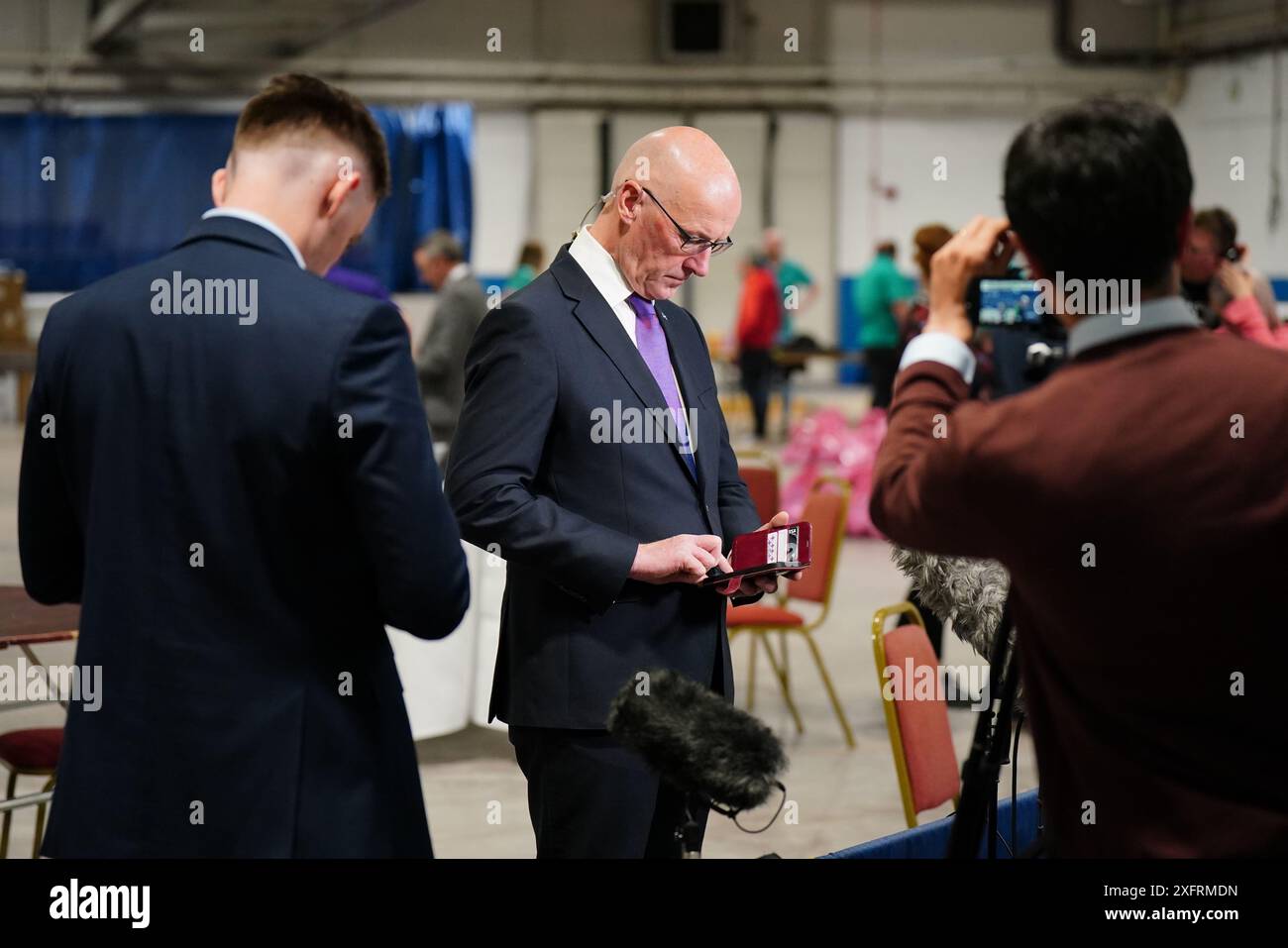 Der schottische erste Minister und SNP-Chef John Swinney schaut während der Wahlperiode 2024 auf sein Telefon in der Ice Hall im Dewars Centre in Perth. Bilddatum: Freitag, 5. Juli 2024. Stockfoto