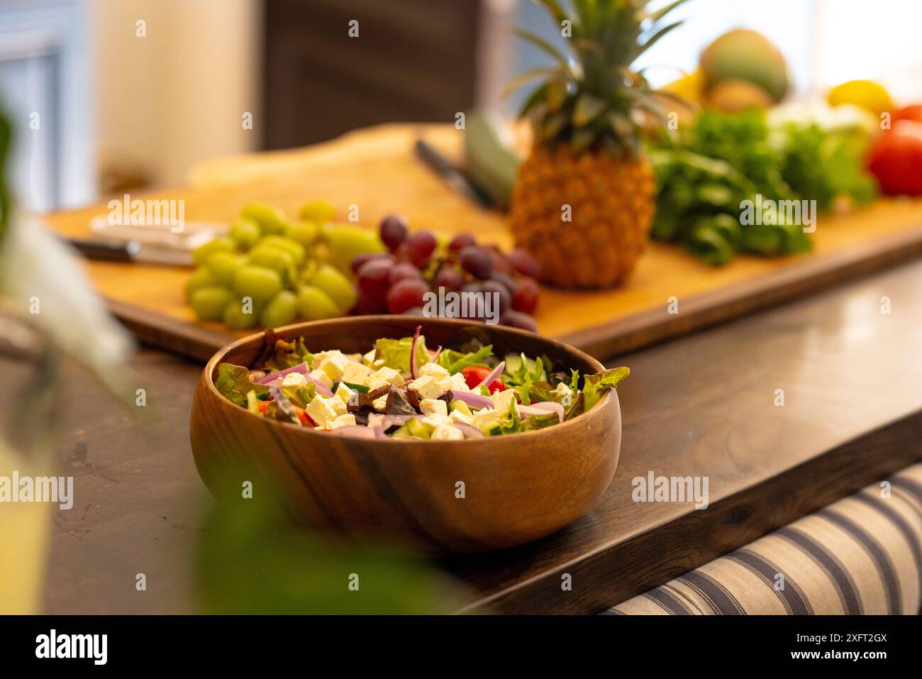 Frischer Salat in Holzschale mit Obst und Gemüse auf der Küchenzeile, Kopierraum Stockfoto