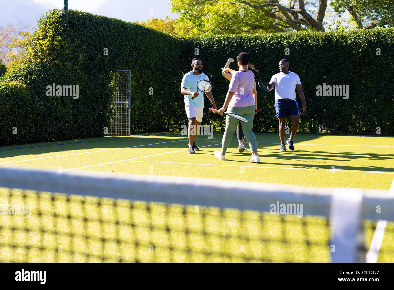 Tennis spielen, eine Gruppe verschiedener Freunde, die an sonnigen Tagen Outdoor-Aktivitäten genießen Stockfoto