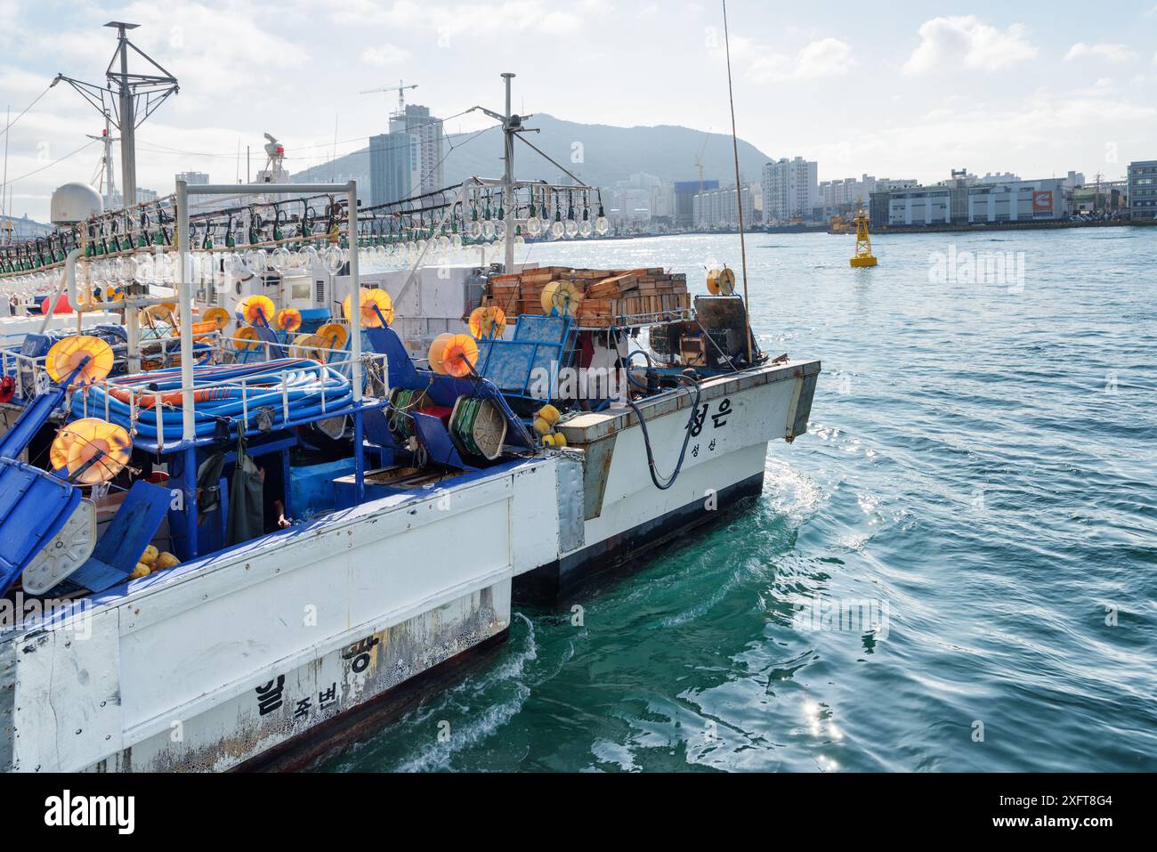 Busan, Südkorea - 7. Oktober 2017: Zwei Fischereifahrzeuge parken im Hafen von Busan. Die Stadt ist auf blauem Himmel zu sehen. Stockfoto
