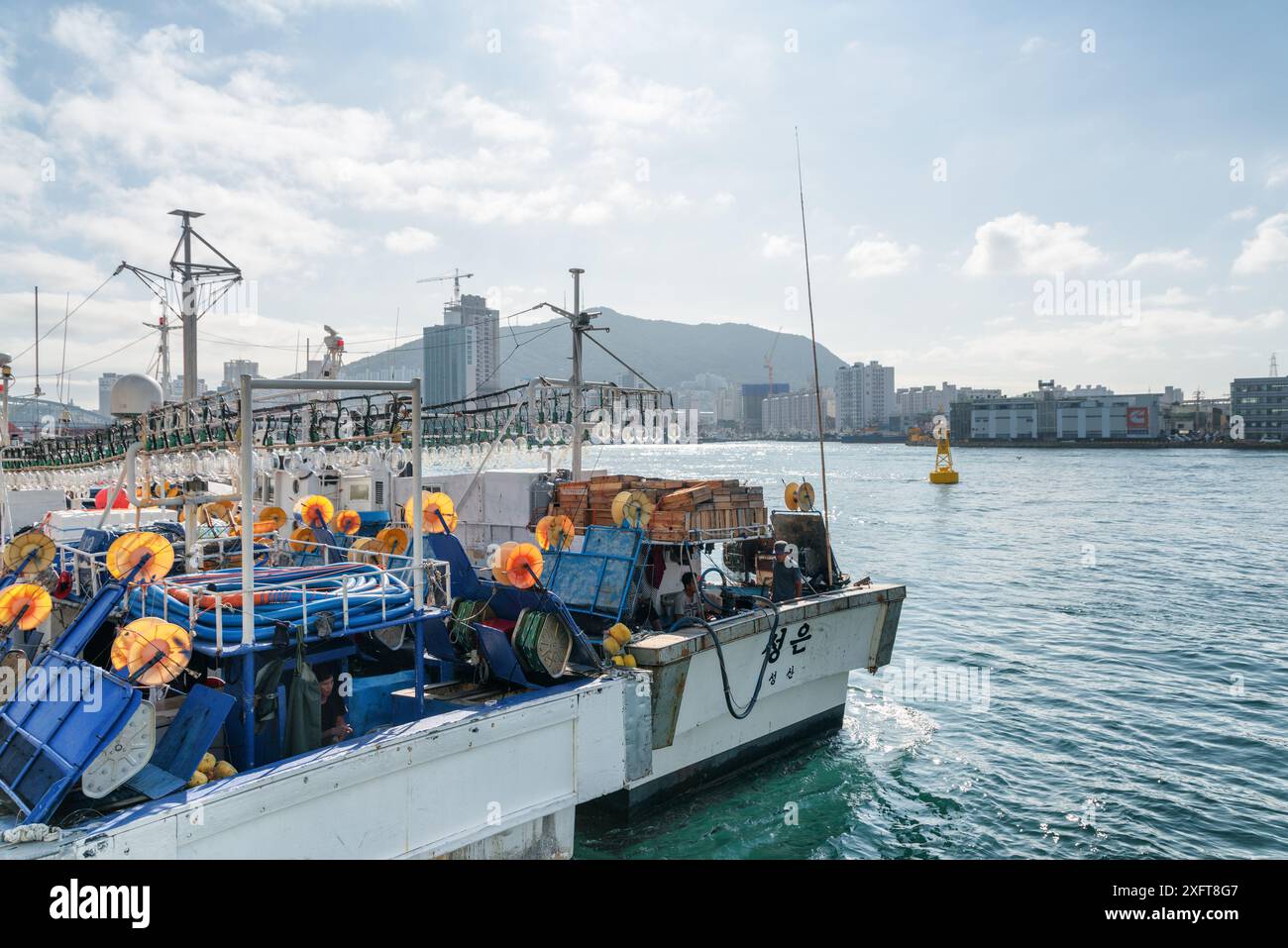 Busan, Südkorea - 7. Oktober 2017: Zwei Fischereifahrzeuge parken im Hafen von Busan. Die Stadt ist auf blauem Himmel zu sehen. Stockfoto