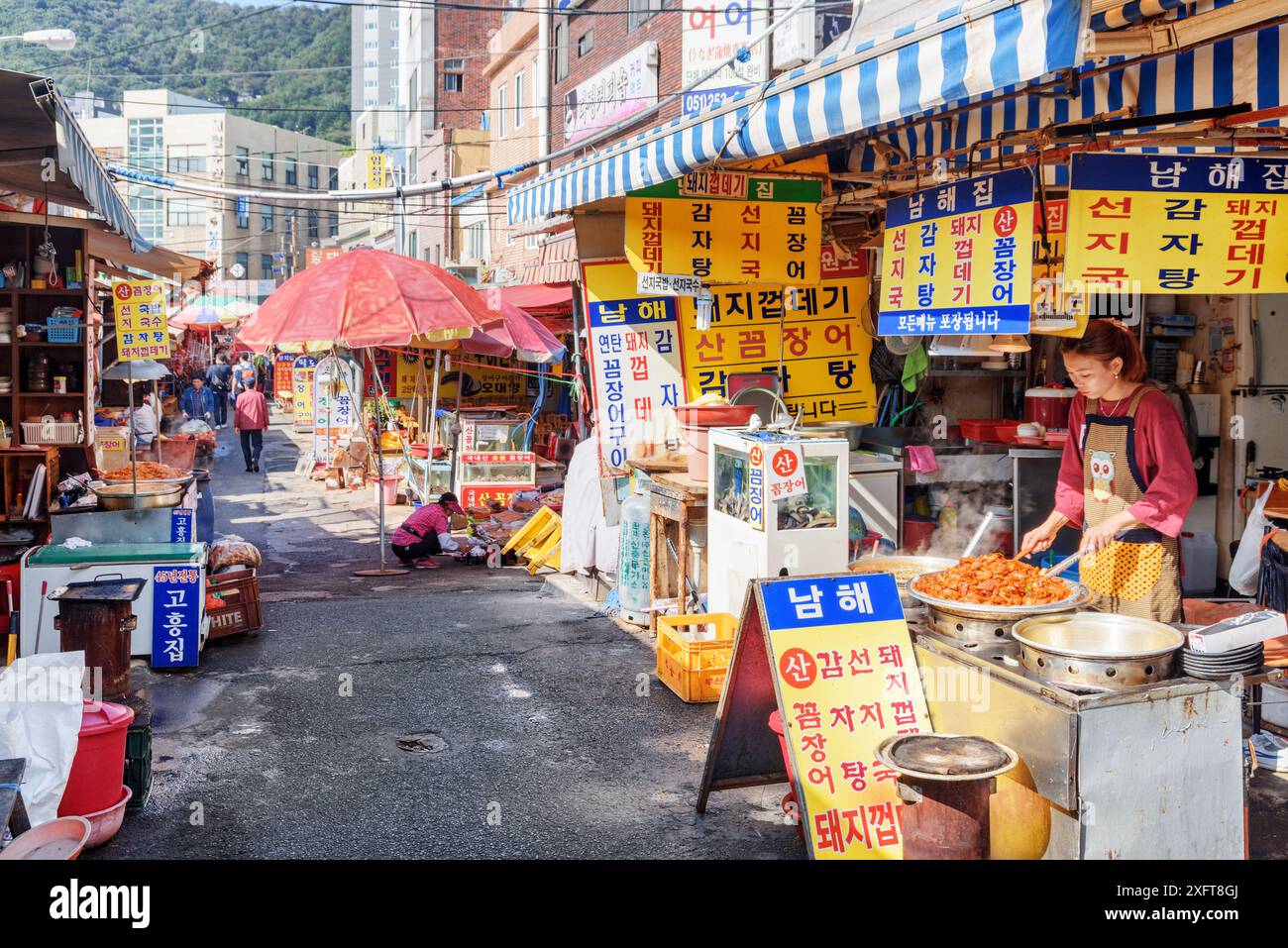 Busan, Südkorea - 7. Oktober 2017: Koreanerin kocht im Straßencafé auf dem Jagalchi Fish Market. Traditionelles Street Food. Stockfoto