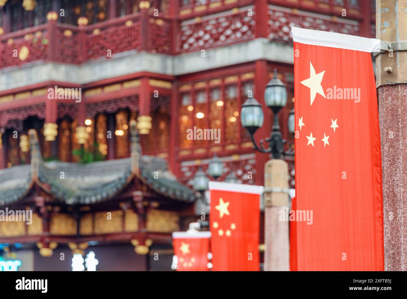 Die Nationalflagge Chinas auf der Straße in der Altstadt von Shanghai. Malerisches traditionelles chinesisches Gebäude ist im Hintergrund zu sehen. Stockfoto