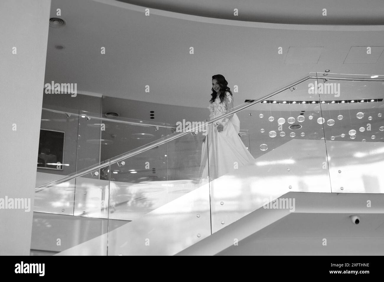 Eine junge Braut in einem langen Hochzeitskleid trifft den Bräutigam in der Hotellobby Stockfoto