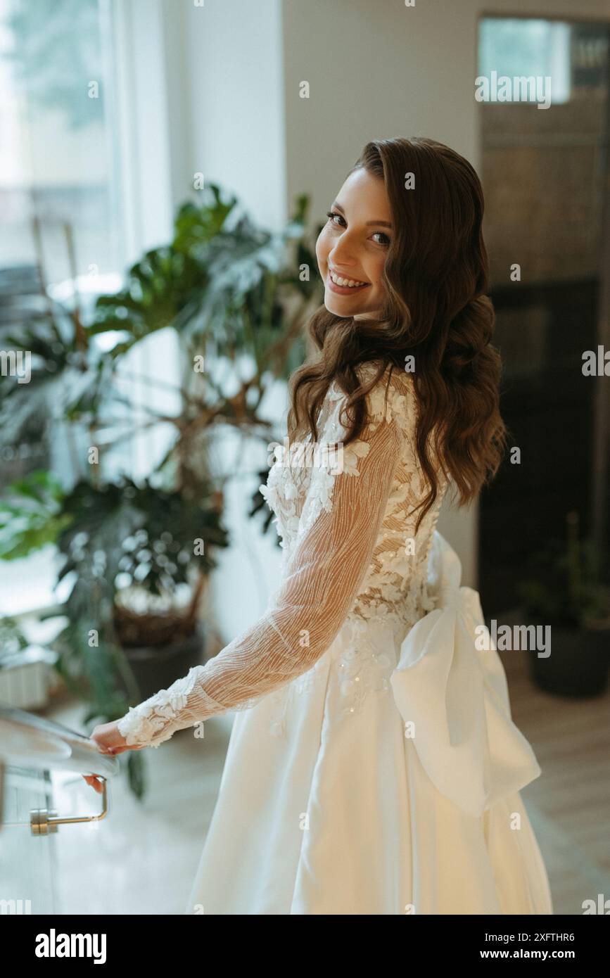 Eine junge Braut in einem langen Hochzeitskleid trifft den Bräutigam in der Hotellobby Stockfoto