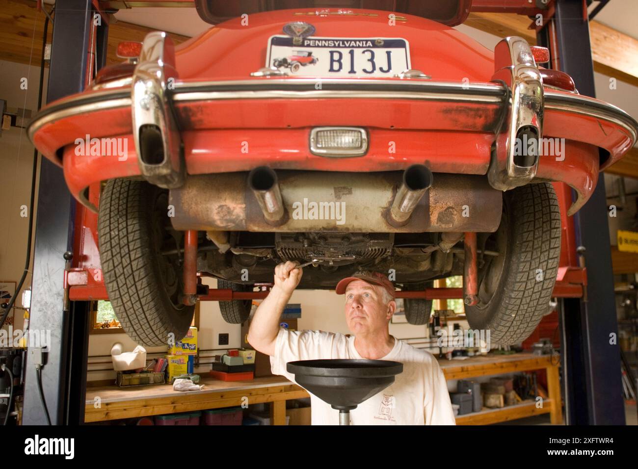 Ein Mann arbeitet an seinem antiken Sportwagen in seiner Garage in Pennsylvania. Stockfoto