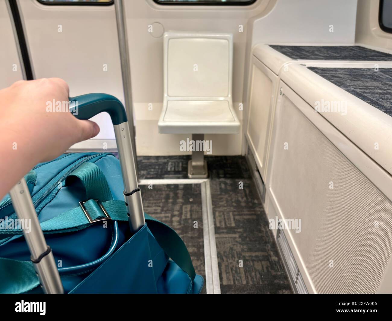 Hand auf blauem Koffer im Zug am Flughafen CVG Stockfoto