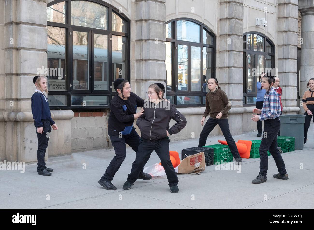 Yeshiva-Schüler und -Mitschüler spielen ein mysteriöses Spiel von Lauf und Tag. Auf den Straßen von Brooklyn an einem warmen Wintertag im Jahr 2024. Stockfoto