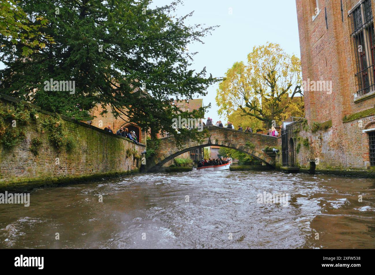 30-10-2014 Brüssel, Belgien - Touristen überqueren eine malerische Brücke über den Brügge-Kanal, von einem Boot aus gesehen Stockfoto