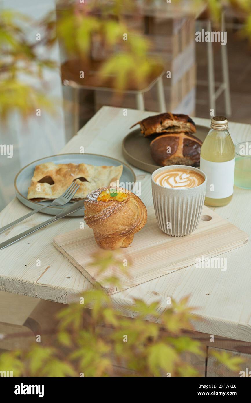 Cappuccino, ein Glas Saft und Gebäck auf einem minimalistischen Coffee Shop-Tisch. Selektiver Fokus. Stockfoto