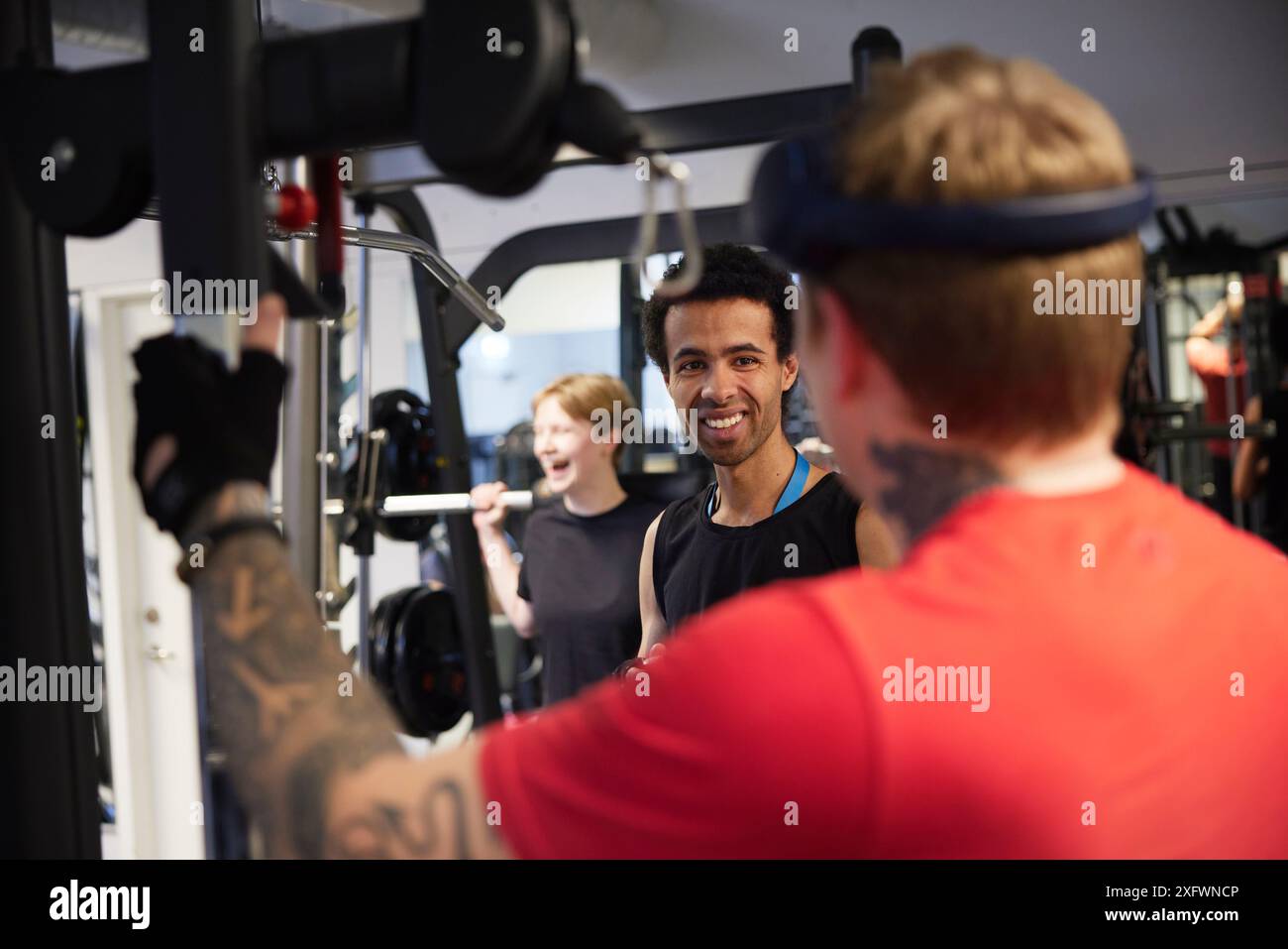 Lächelnder Mann, der mit einem Freund im Fitnessstudio spricht Stockfoto