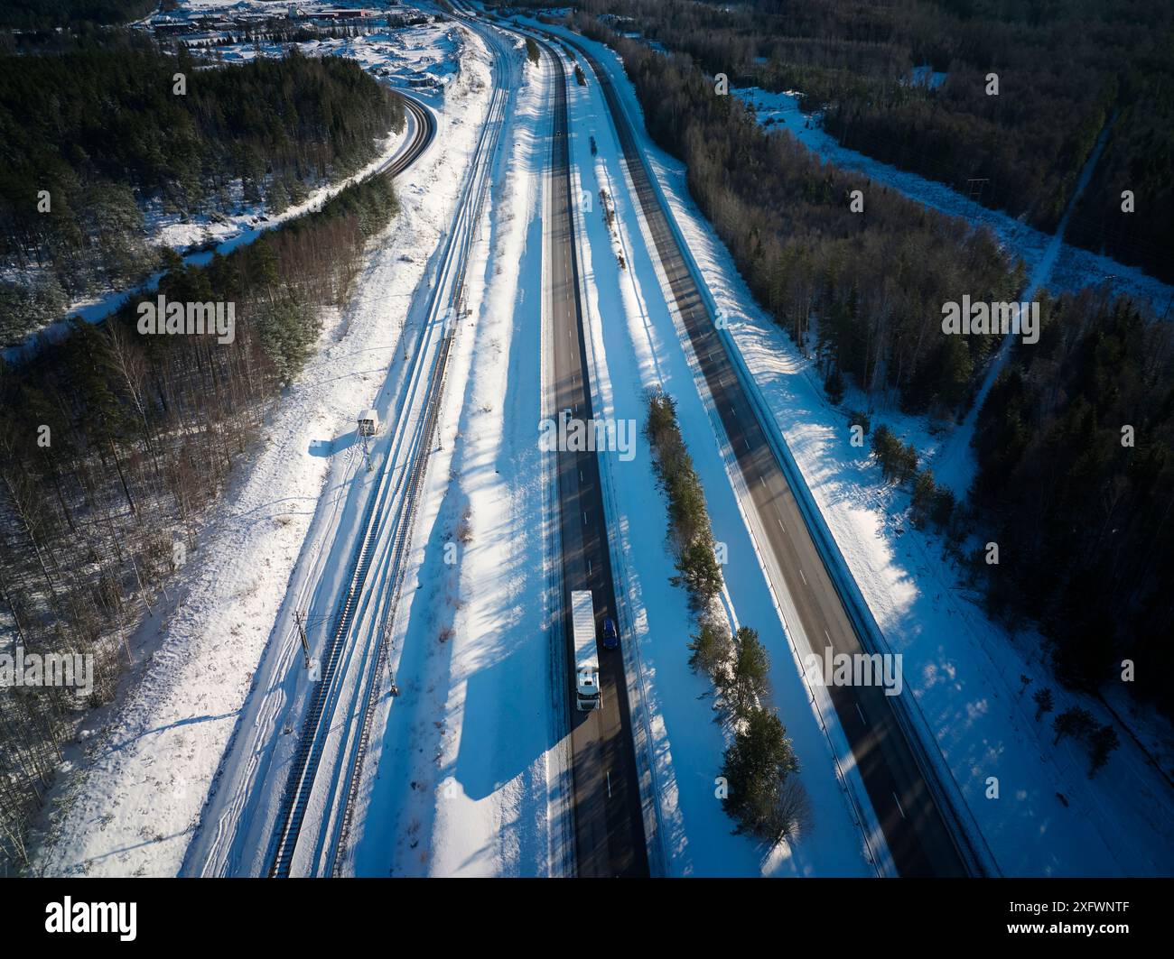 Drohnenblick auf Autobahn und Eisenbahngleise inmitten von Schnee Stockfoto