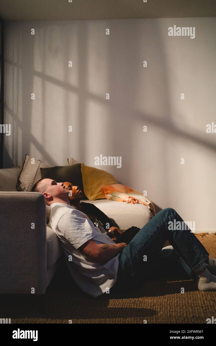 Seitenansicht eines jungen Paares, das sich zu Hause in der Nähe des Sofas liegend Stockfoto