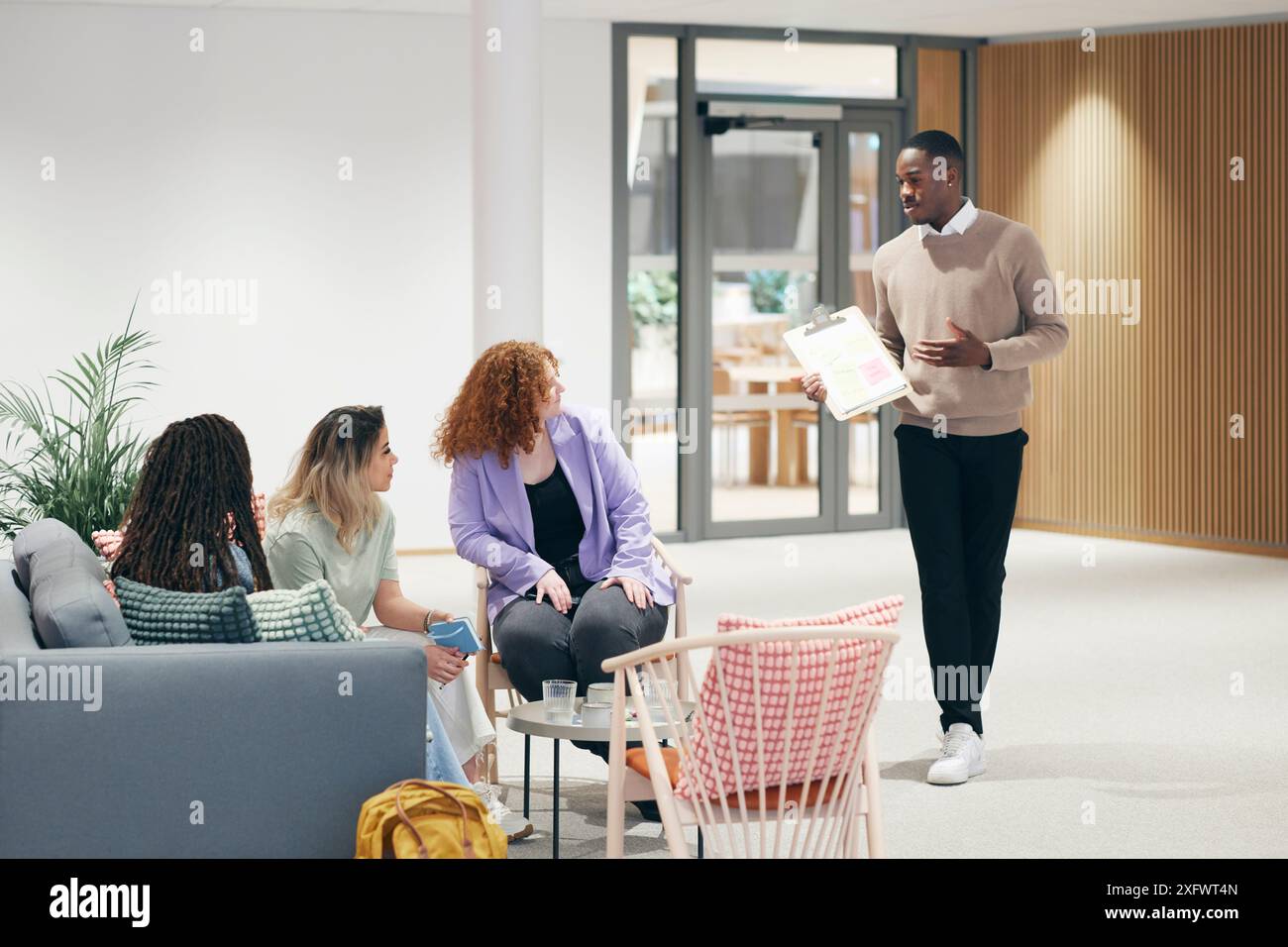 Junger Geschäftsmann, der weiblichen Kollegen in der Bürolobby Ideen erklärt Stockfoto