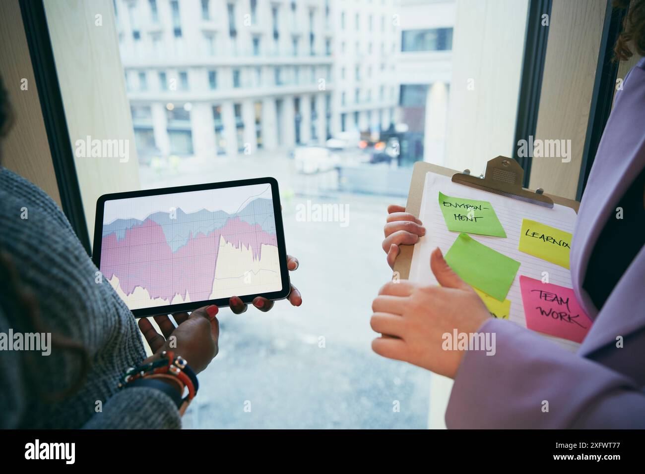 Zugeschnittenes Bild von Geschäftsfrauen, die ein digitales Tablet und eine Zwischenablage im Büro halten Stockfoto