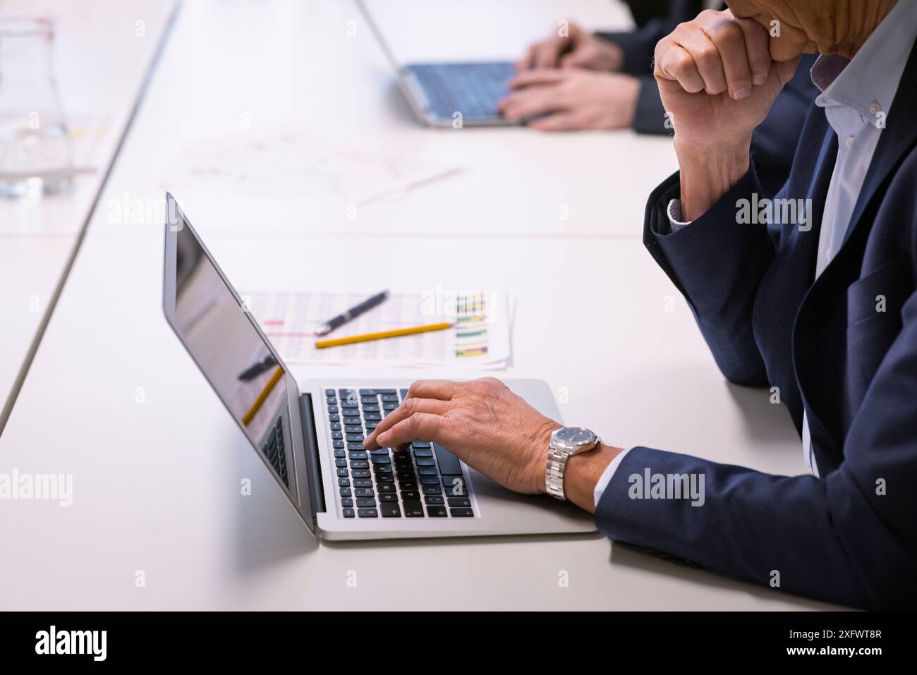 Mittelteil eines Geschäftsmannes mit Laptop am Tisch im Büro Stockfoto