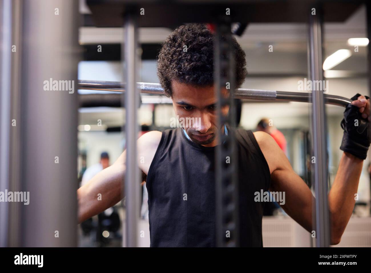 Fokussierter junger Mann beim seitlichen Pulldown-Gewichtheben im Fitnessstudio Stockfoto