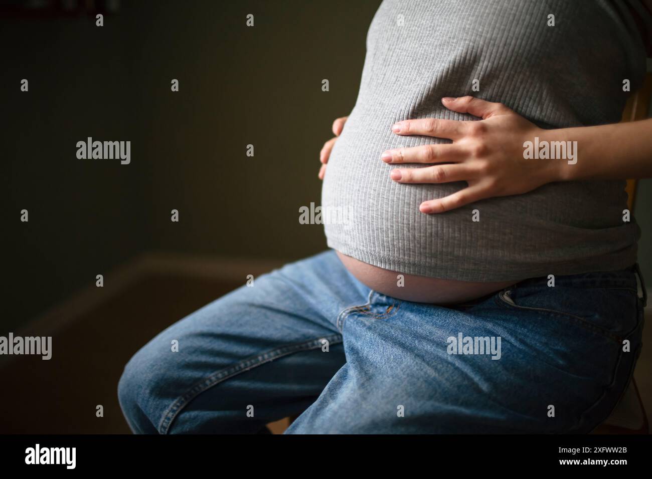 Mittelteil der schwangeren Frau mit Händen auf Magen Stockfoto