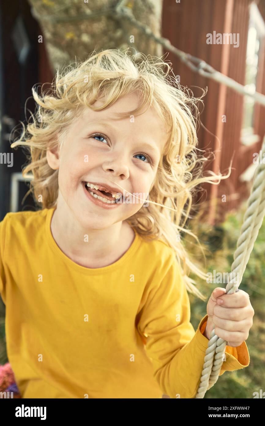 Glückliches Mädchen, das im Hinterhof schwingt Stockfoto