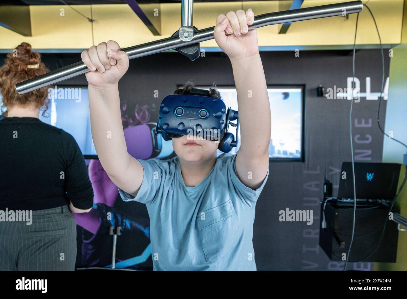 Jugendliche, die mutig auf die VR-Plank treten, tragen eine VR-Brille (Virtual Reality), die sanft die Planke über die Straßen von Melbou treten Stockfoto