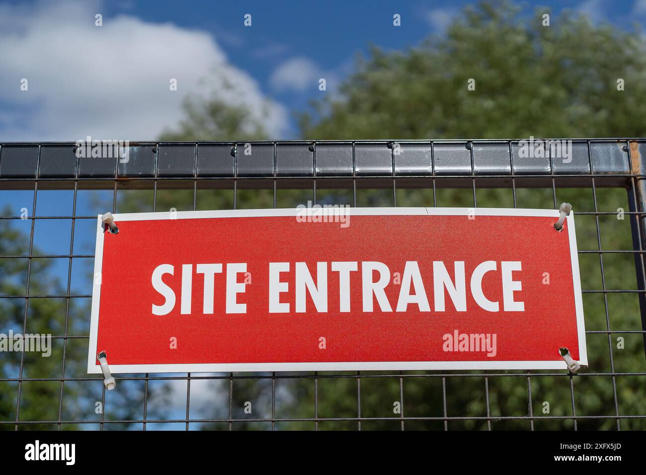 Schild für den Ortseingang in Rot an einem Stahlgitter-Tor befestigt. Stockfoto
