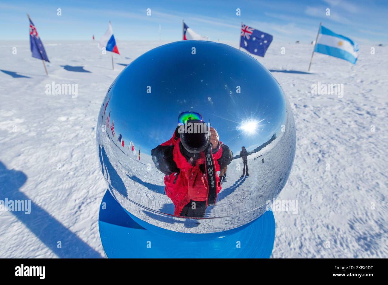 Die Tierfotografin Sue Flood spiegelt sich in einem Marker am zeremoniellen Südpol 90 Grad Süd in der Nähe des Scott-Amundsen-Basislagers in der Antarktis. Dezember 2016 Stockfoto