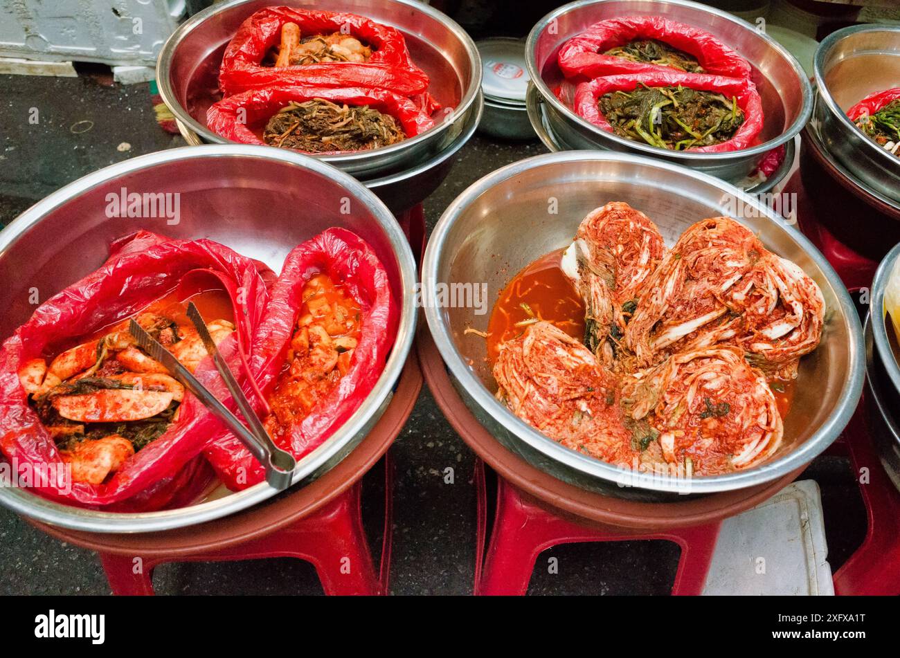 Lebhaftes koreanisches Street Food: Kimchi und andere fermentierte Gerichte in Metallschalen, die traditionelle kulinarische Kultur zeigen. Stockfoto